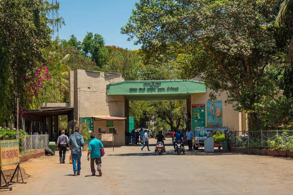 A gate with a sign reading "Sanjay Gandhi National Park Mumbai" and a "NO PARKING" sign.