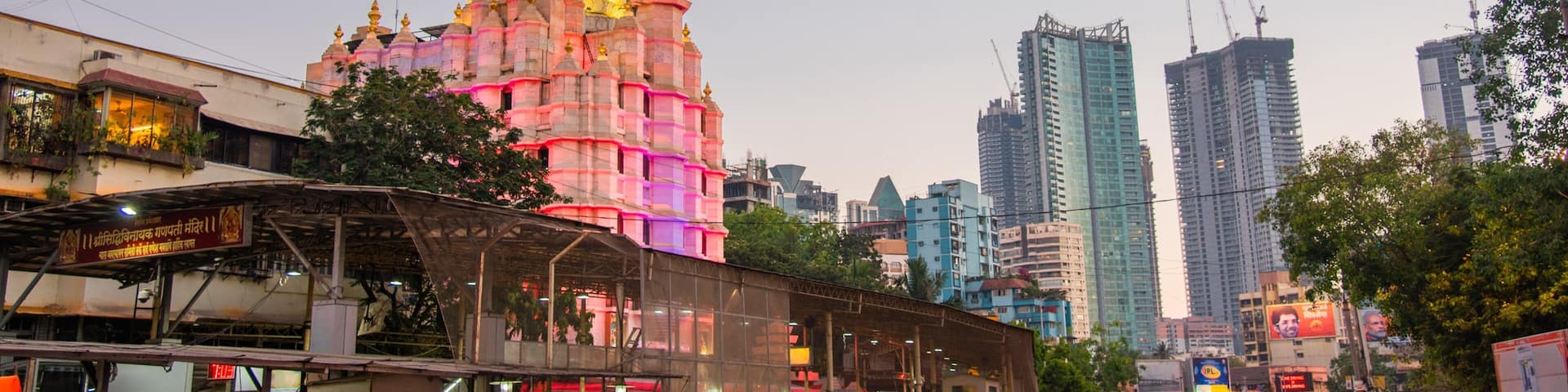 A busy urban street with a brightly lit temple in the background.