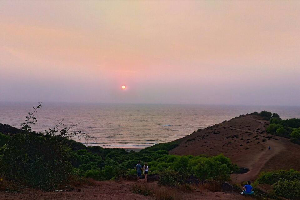 Un capvespre sobre un paisatge costaner amb un camí de terra que condueix a una platja.