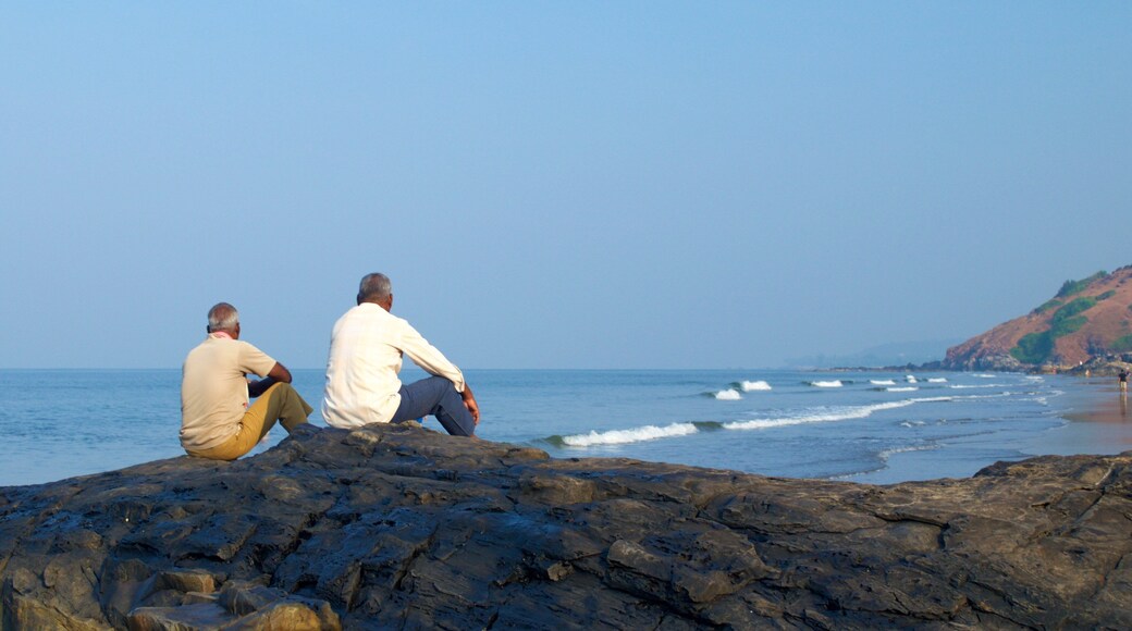Vagator Beach featuring rocky coastline as well as a small group of people