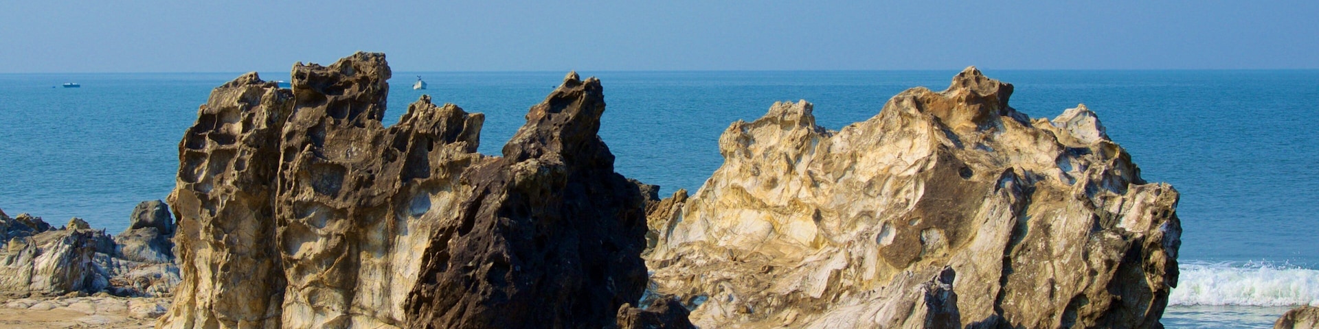 A rocky coastline with jagged formations and a clear blue sea.
