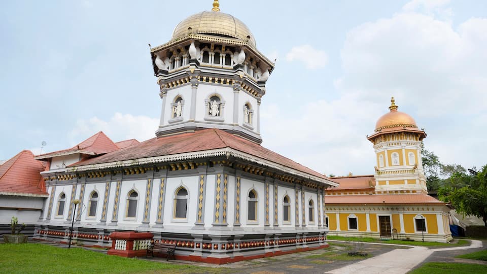 A historic building with a white facade and a golden dome, featuring arched windows and a red roof.