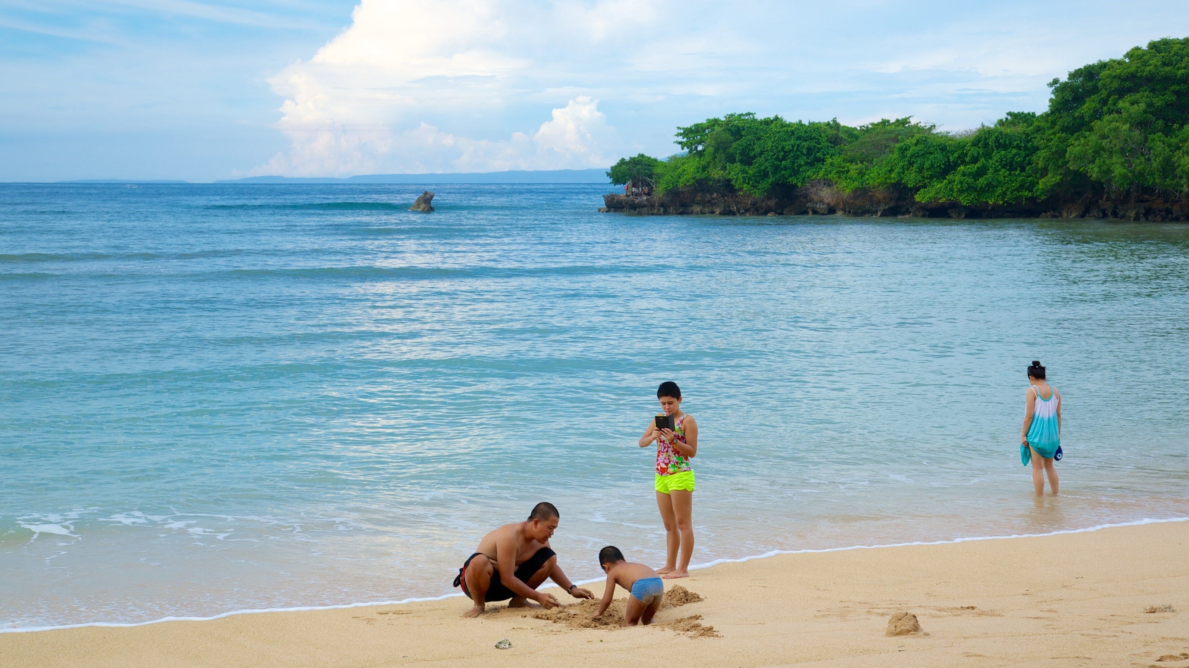 Nusa Dua Beach featuring tropical scenes and a beach as well as a small group of people
