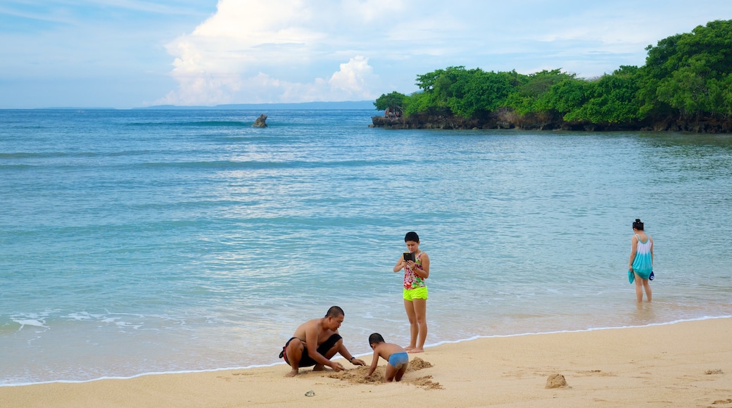 Nusa Dua Beach which includes tropical scenes and a sandy beach as well as a family