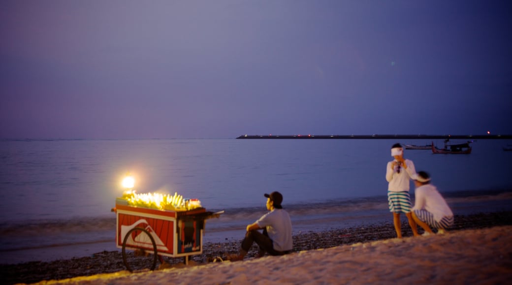 Jimbaran Beach which includes a beach and night scenes as well as a small group of people