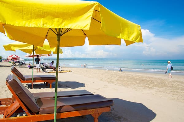Ein Strand mit gelben Sonnenschirmen, Liegestühlen und einer Flagge.
