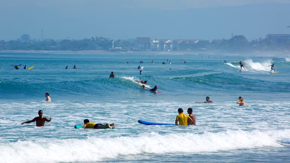 Una playa concurrida con surfistas y nadadores en el océano.