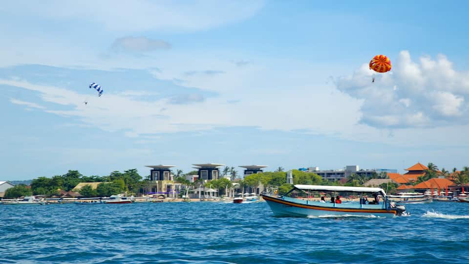 A boat on a calm sea with buildings and a clear sky in the background.