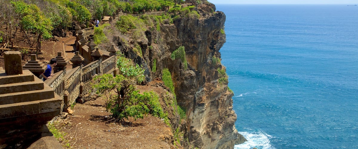 Uluwatu Temple which includes a temple or place of worship, rocky coastline and landscape views