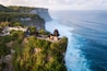 A coastal cliffside with a traditional thatched-roof structure overlooking the ocean.