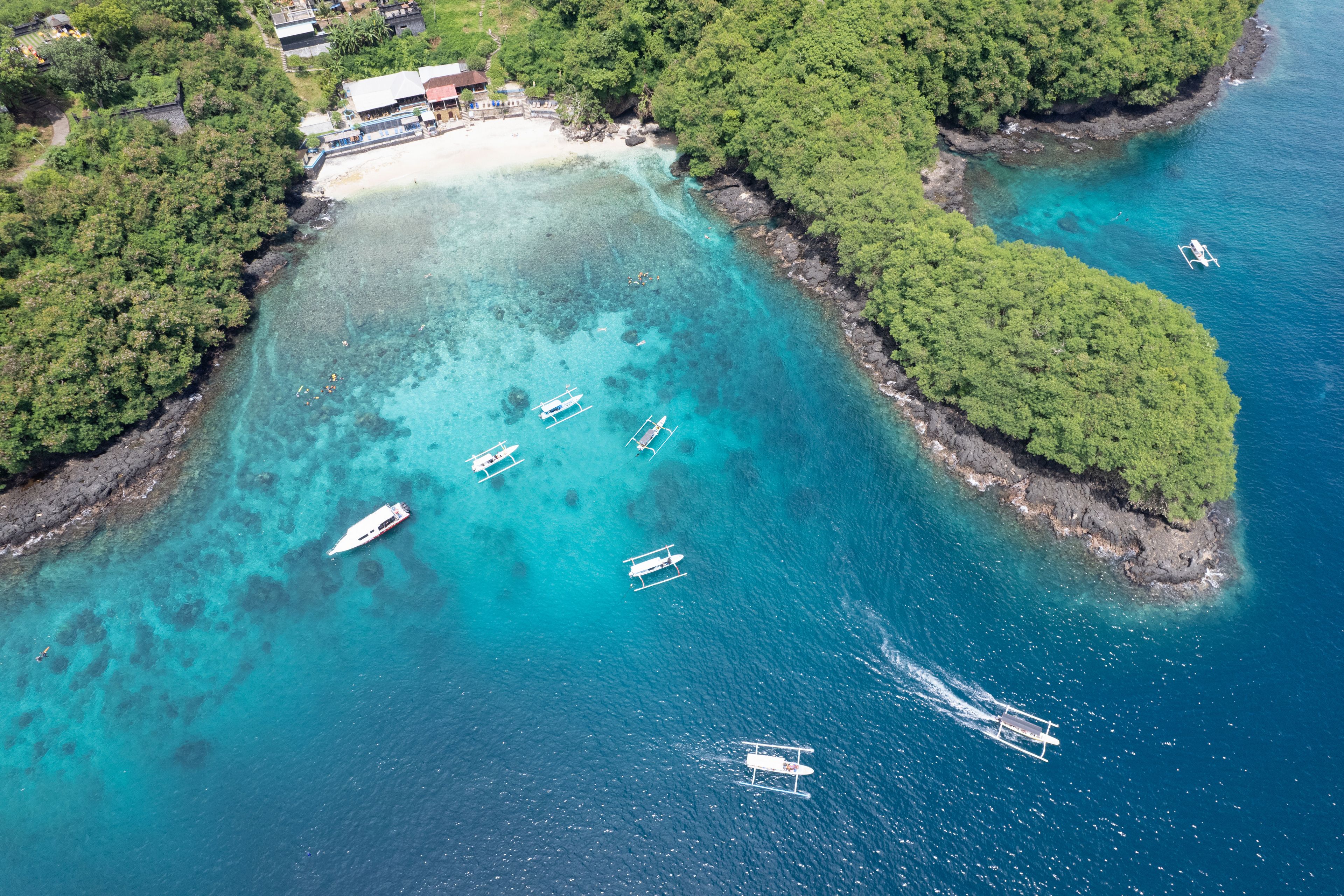 Aerial view of traditional Balinese boats (Jukung) and divers in Blue Lagoon. Padangbai, Bali, Indonesia.