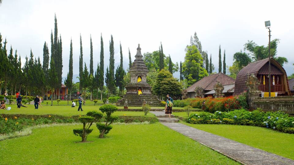 A temple complex with a central stupa, surrounded by lush greenery and tall trees.