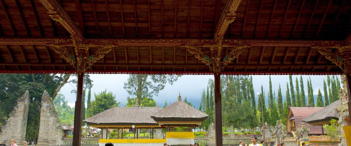 A traditional pavilion with ornate pillars and a thatched roof, surrounded by lush greenery and ancient stone structures.