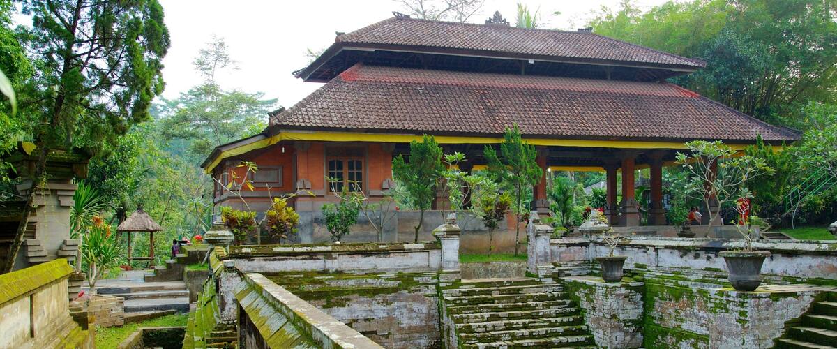 A traditional building with a tiled roof, surrounded by lush greenery and stone steps leading up to it.