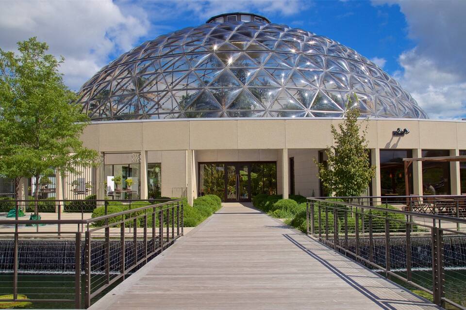 A large geodesic dome structure with a wooden walkway leading to its entrance.