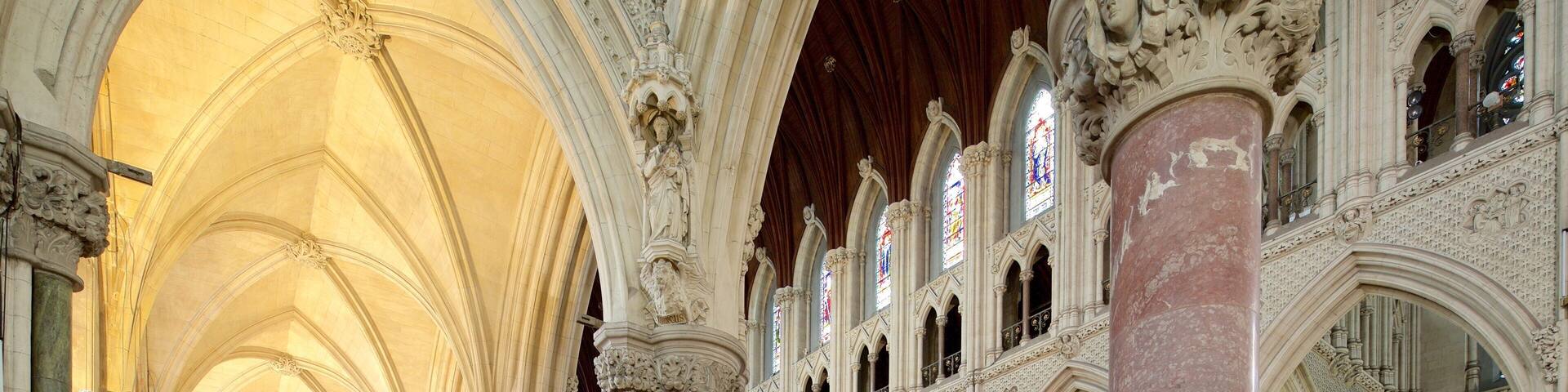 A cathedral interior with high vaulted ceilings, ornate columns, and stained glass windows.