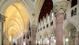A cathedral interior with high vaulted ceilings, ornate columns, and stained glass windows.