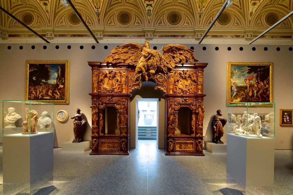 An ornate gallery with classical sculptures and paintings.