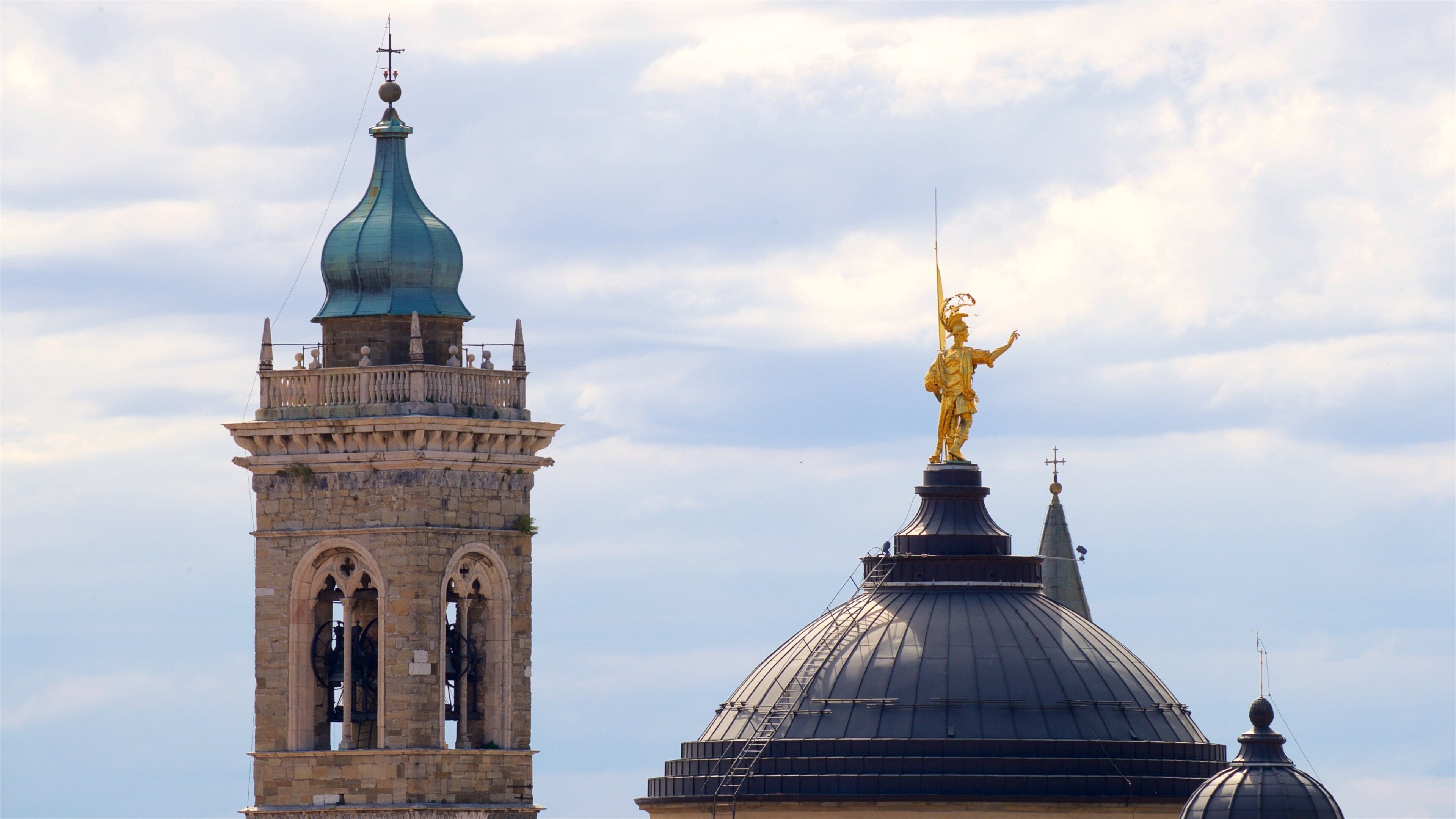 A historic tower with a clock and a golden statue on a dome.
