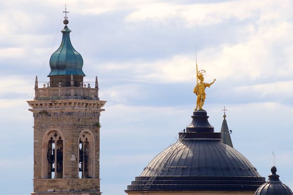 A historic tower with a clock and a golden statue on a dome.