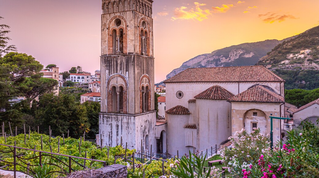 Ravello, Italy. August 9th, 2020. Breathtaking sunset over the Ravello Cathedral and its bell tower framed between plants and colorful oleander flowers.