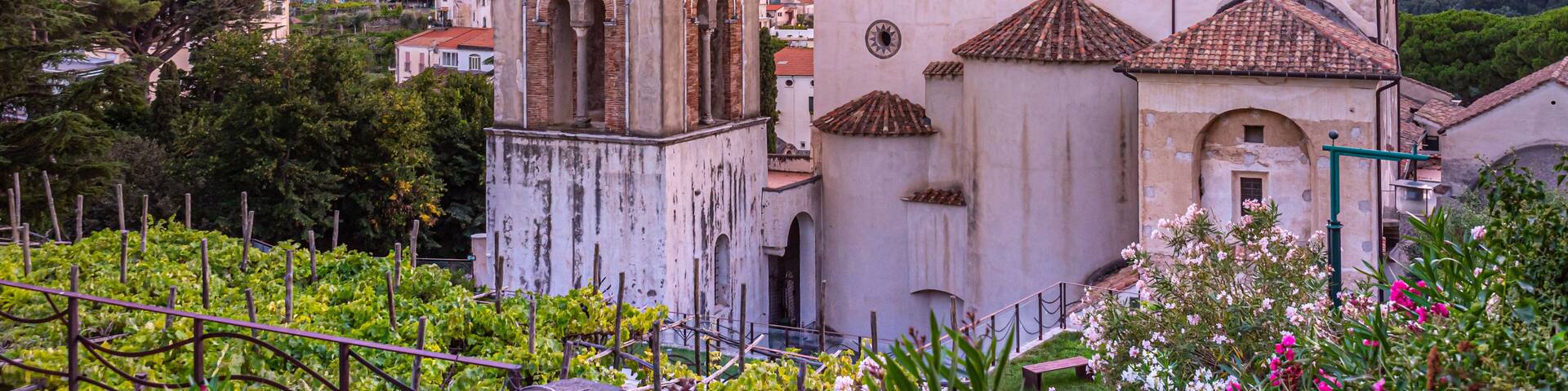 Ravello, Italy. August 9th, 2020. Breathtaking sunset over the Ravello Cathedral and its bell tower framed between plants and colorful oleander flowers.