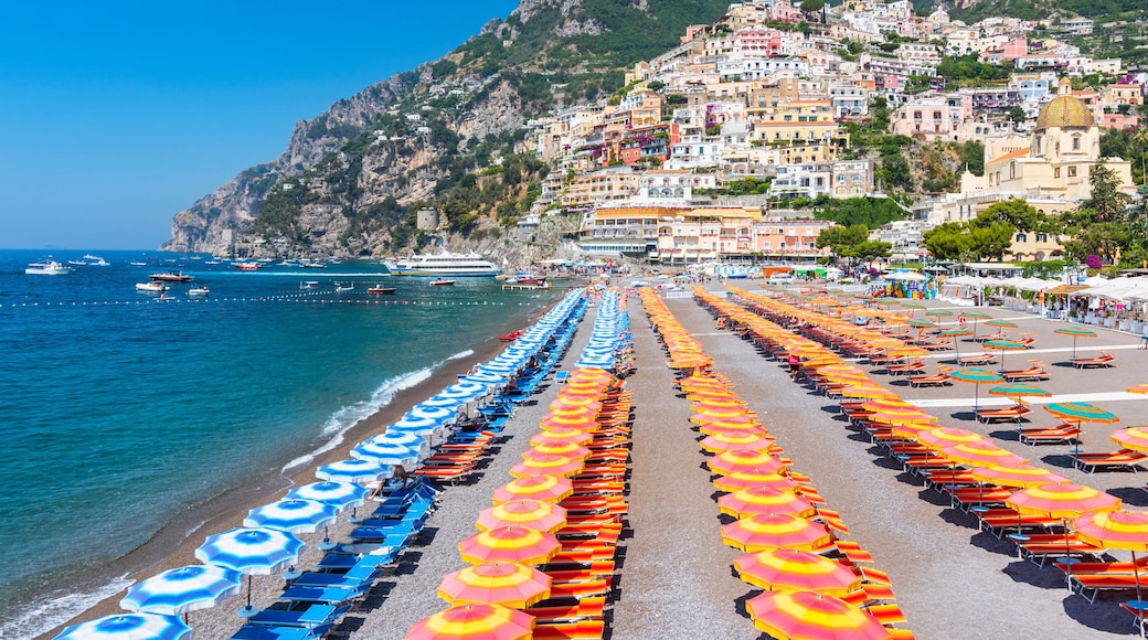 View of famous rows of blue and orange beach umbrellas on Positano Beach, Amalfi Coast, Italy.
