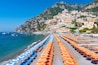 View of famous rows of blue and orange beach umbrellas on Positano Beach, Amalfi Coast, Italy.