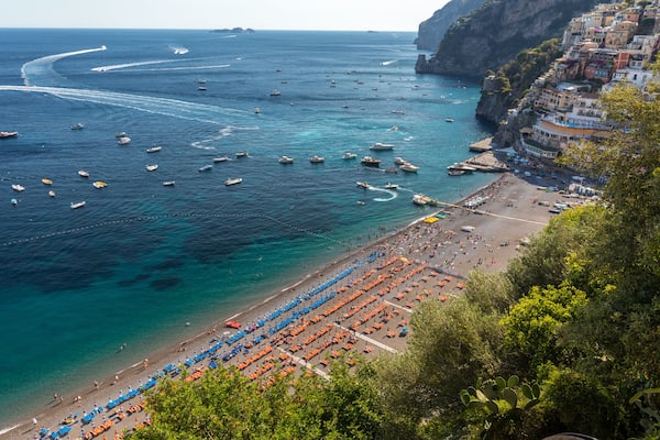 The main beach in Positano, Spiaggia Grande, with its bright orange and blue beach umbrellas and the sparkling blue sea of the Amalfi Coast.