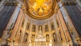 Ein prachtvolles Kircheninnere mit einer großen, zentralen Statue, aufwendigen Goldverzierungen und einem detailreichen Deckenfresko.