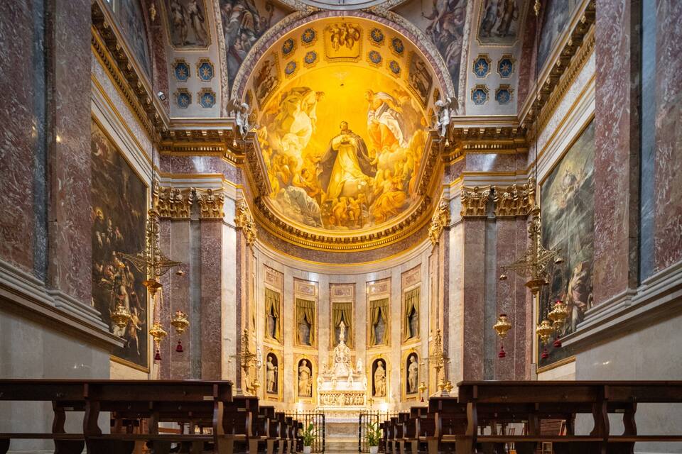 Interior de iglesia con una gran cúpula dorada, columnas de mármol y pinturas religiosas.