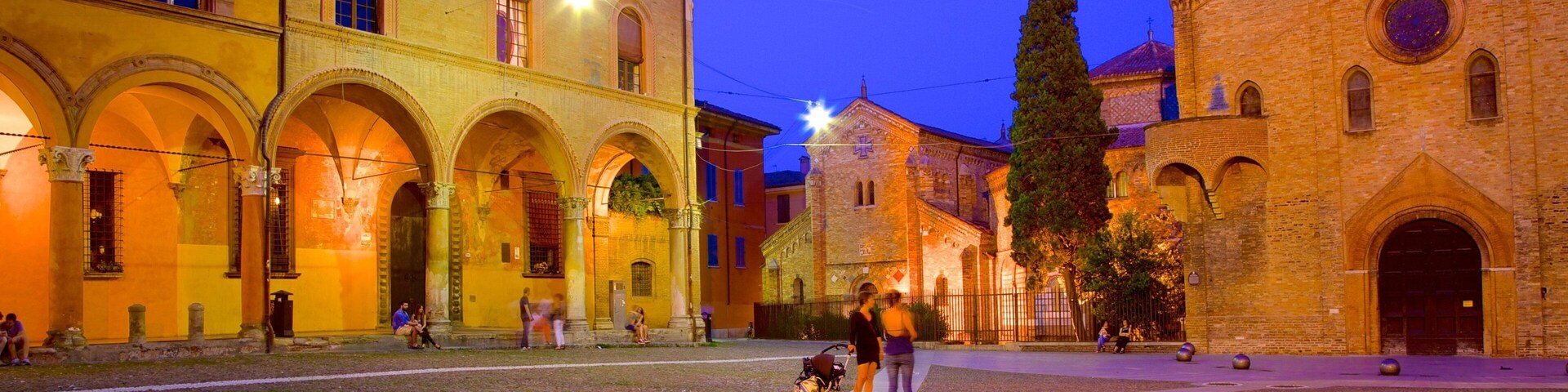Uma praça de paralelepípedos com edifícios históricos, incluindo uma igreja com cúpula e arcos.
