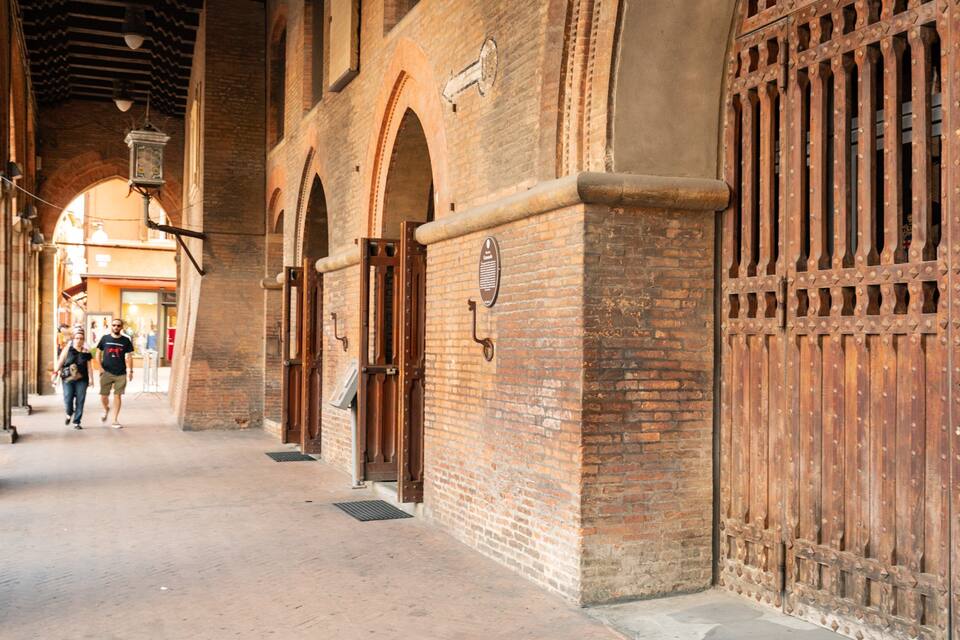 A brick building with arched doorways and a large wooden gate.