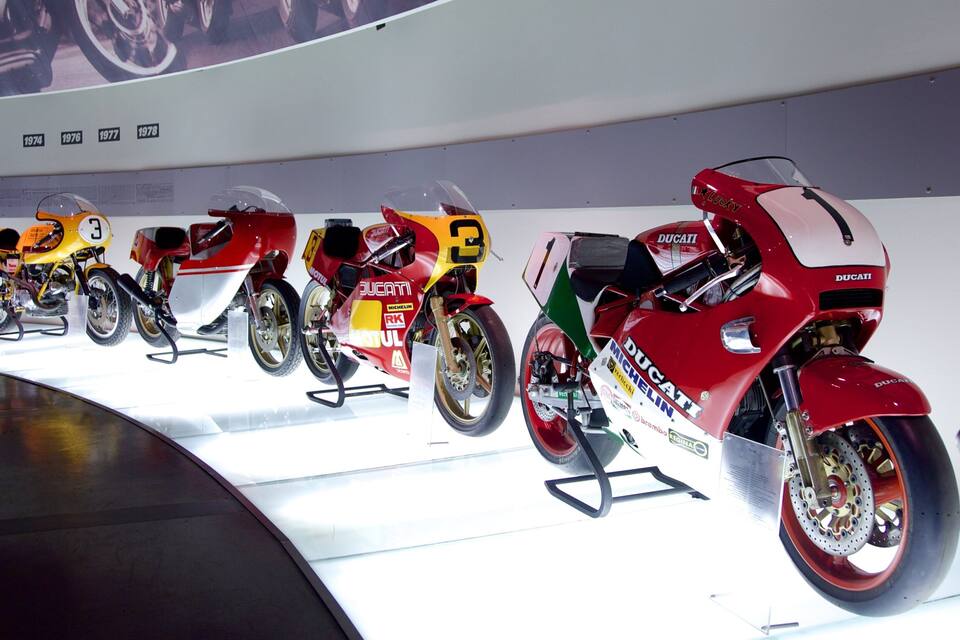 Une rangée de motos de course anciennes est exposée.