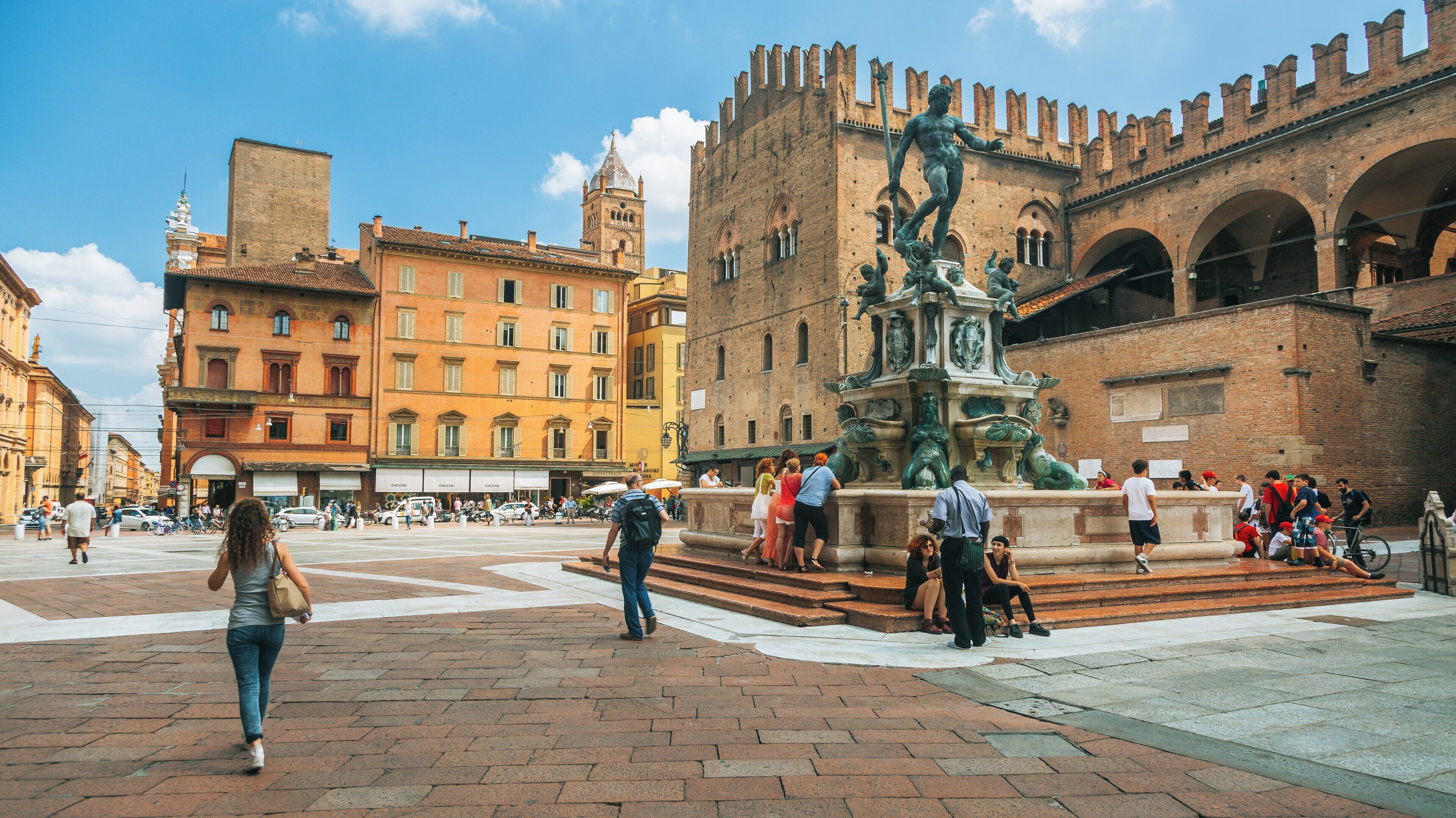 Fountain of Neptune stands proudly in the historic center of Bologna, showcasing its intricate design amidst lively street activity and vibrant buildings
