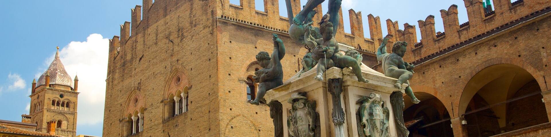 A statue of a muscular figure with a trident, standing on a pedestal in front of a historic building with arched windows and a tower.