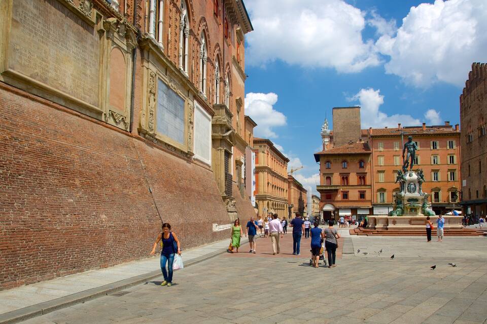 A historic square with a large brick wall, a fountain, and classical architecture.