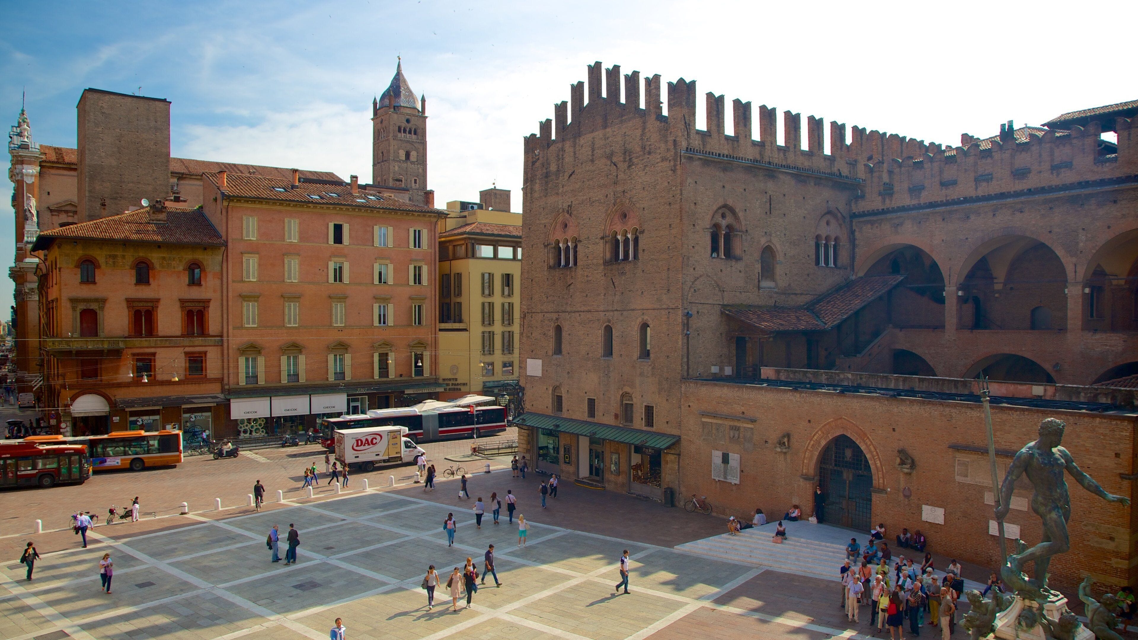 A historic square with a prominent castle, a church, and a statue.