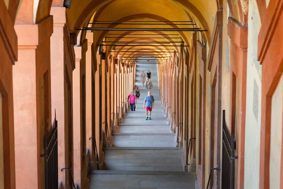 A long, arched corridor with stone walls and metal railings.
