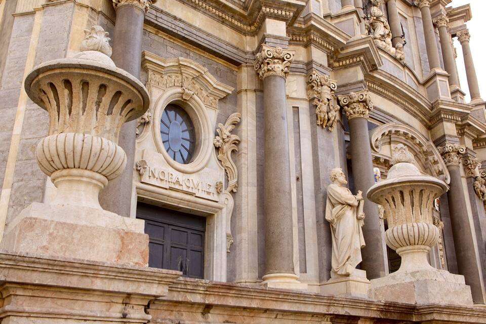 Un edificio histórico con columnas ornamentadas, un reloj y estatuas.