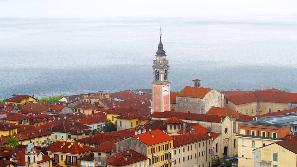 A coastal town with red-roofed buildings, a prominent clock tower, and a view of the sea.