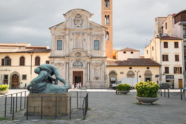Une place avec une statue, une église et des bâtiments environnants.
