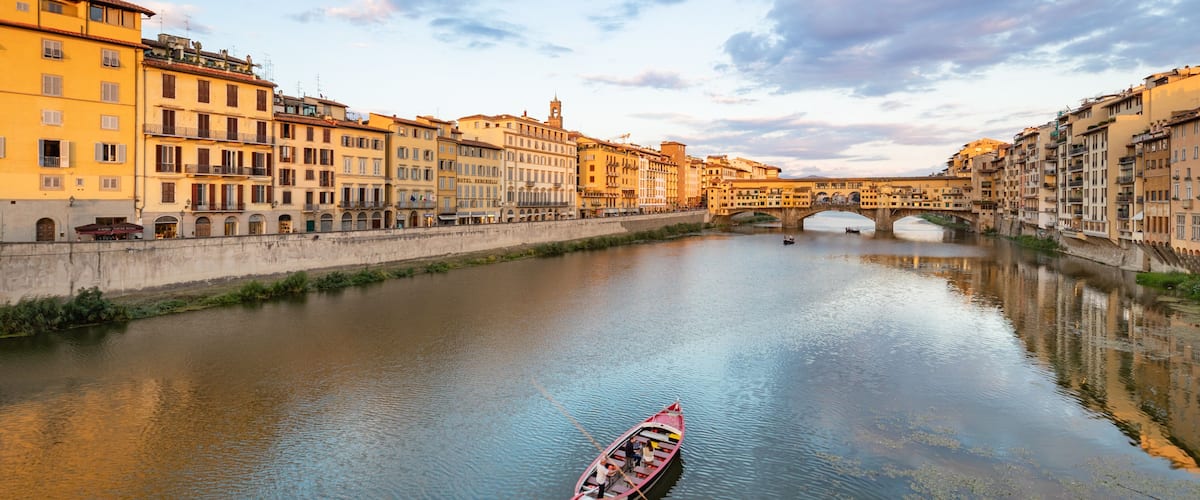 A river with a boat, buildings, and a bridge.
