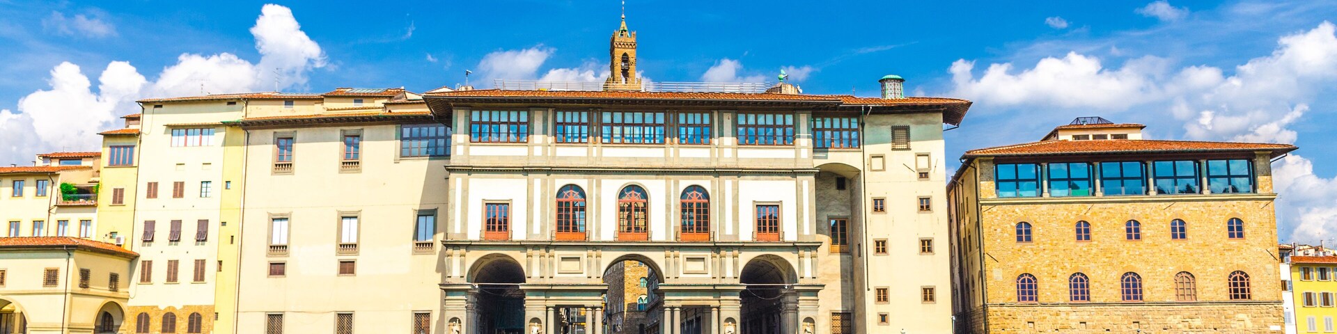 Museo Galileo museum, Gallerie degli Uffizi gallery and buildings on embankment promenade of Arno river in historical centre of Florence city, blue sky white clouds background, Tuscany, Italy
