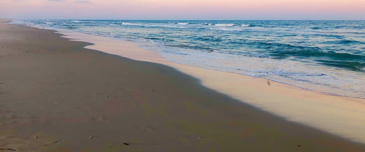 A beach with gentle waves and a clear sky.