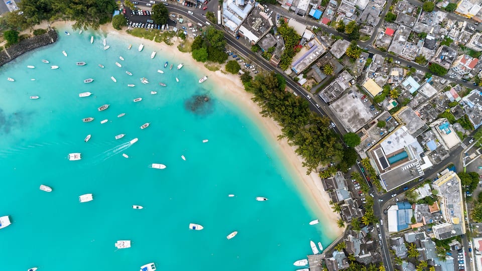 A coastal city with a beach, boats, and dense urban buildings.