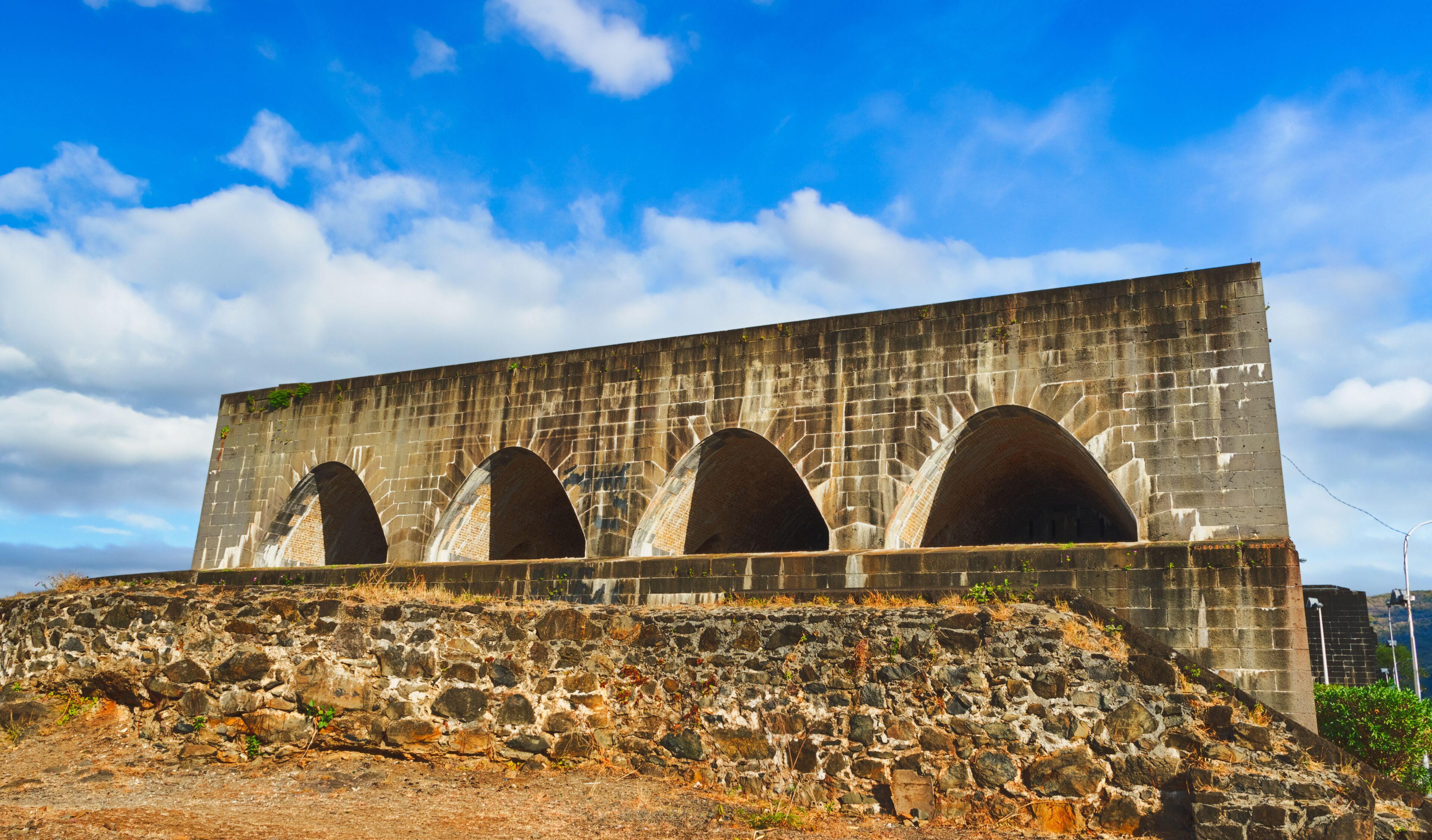 A large stone structure with multiple arched openings and a stone ramp leading up to it.