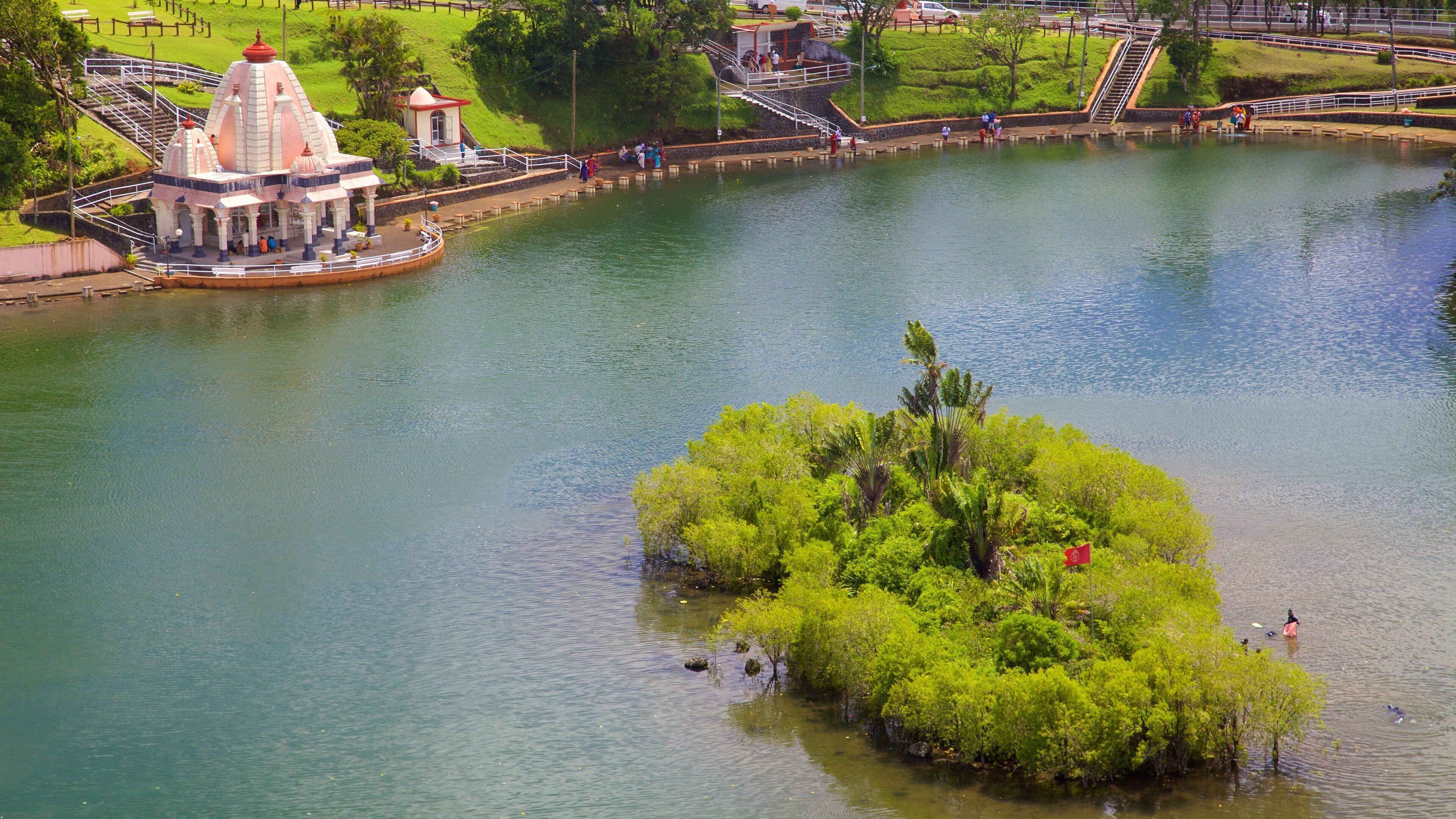 A river with a small island of lush greenery and a temple-like structure on the left bank.
