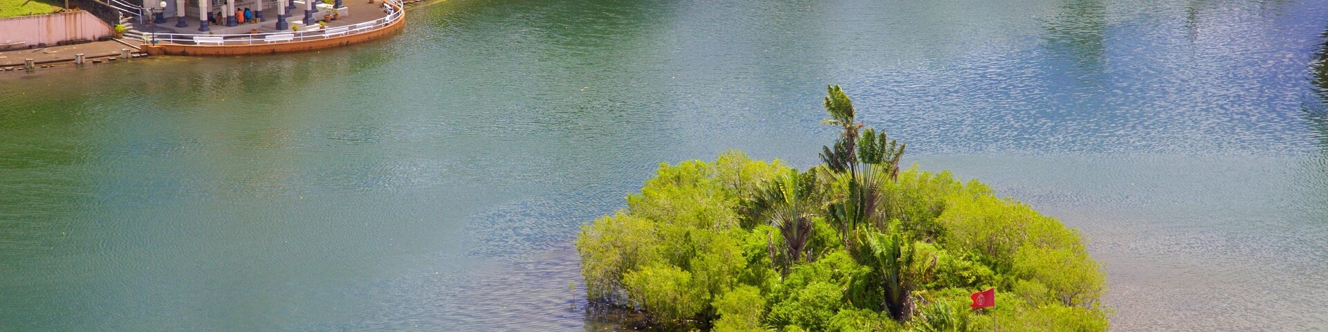 A river with a small island of lush greenery and a temple-like structure on the left bank.