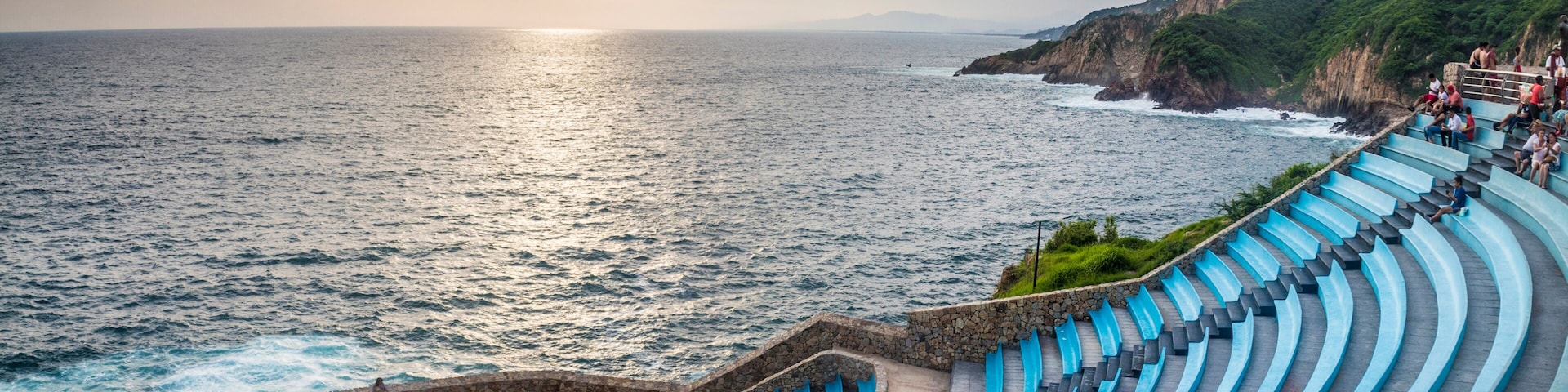 Un anfiteatro frente al mar con escalones azules y un escenario circular, con vistas al océano.